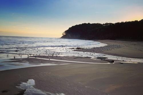 a beach with a group of people in the water at Casa Yaya confortllanes in Colunga