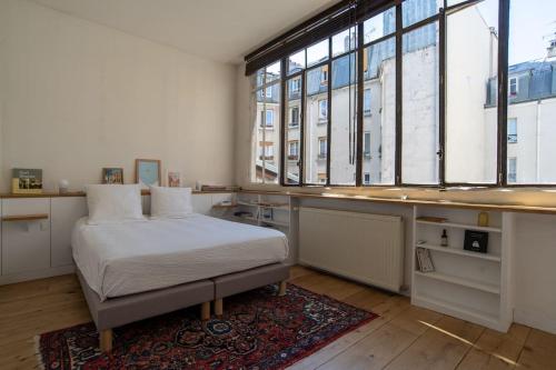 une chambre avec un lit et une grande fenêtre dans l'établissement Sublime loft avec verrières sur le Canal St Martin, à Paris