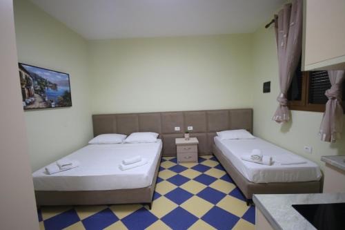 two beds in a small room with a kitchen at Vila Bajrami in Vlorë