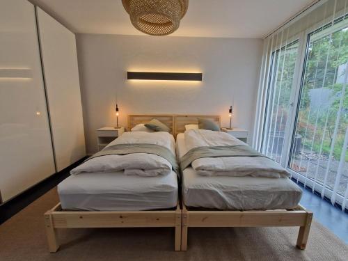 two beds in a bedroom with a large window at Gästezimmer Gerlafingen in Gerlafingen