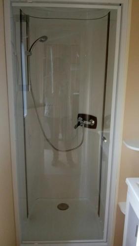 une douche avec une porte vitrée dans une salle de bain dans l'établissement MOBILHOME CHEZ SYLVIE AU CAMPING DE PUJOL, à Argelès-sur-Mer
