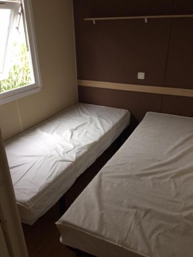 deux lits dans une petite pièce avec une fenêtre dans l'établissement MOBILHOME CHEZ SYLVIE AU CAMPING DE PUJOL, à Argelès-sur-Mer