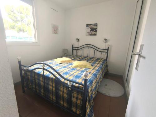 - une chambre dotée d'un lit avec une couverture tressée et une fenêtre dans l'établissement 5070 Mas de la pinède 300, au Cap d'Agde