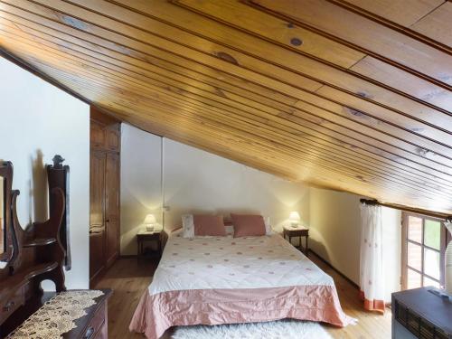 une chambre avec un lit avec un plafond en bois dans l'établissement Gîte en pierre avec piscine, à Cordes-sur-Ciel