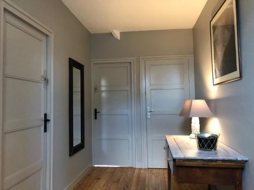 a hallway with white doors and a table with a lamp at Maison bord de mer et centre Feart in Dinard
