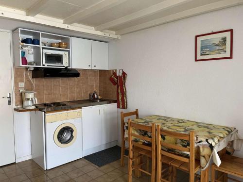 une cuisine avec une table et une machine à laver dans l'établissement Maison cabine mezzanine 6 couchages PORT LEUCATE NATURISME PL070-103, à Port-Leucate