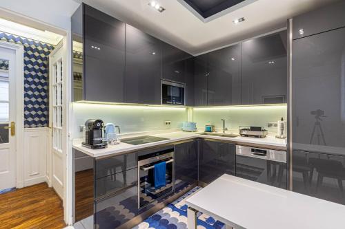 - une cuisine avec des placards noirs et un évier dans l'établissement GuestReady - Appartement Spacieux et Élégant, à Paris