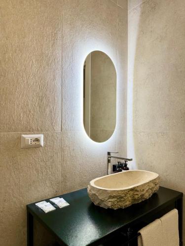 a bathroom with a stone sink and a mirror at Anno13Suites in Naples