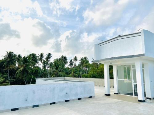 a white house with a glass door on a patio at Sevenday Hotel in Marawila