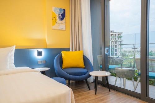 a hotel room with a bed and a yellow pillow at FLAMINGo TÒA IBIZA, Hải Tiến in Thanh Hóa