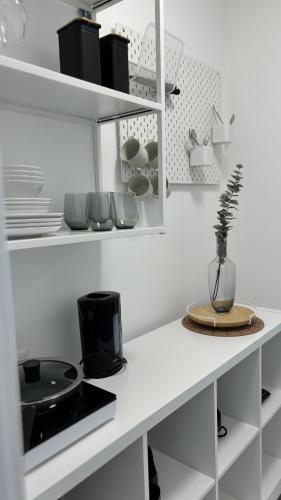 a white kitchen with white shelves and a table at Langenzersdorf Apartment in Langenzersdorf