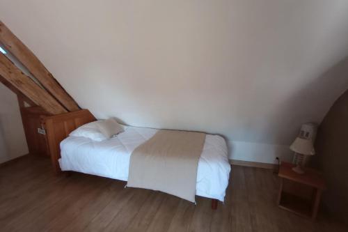 a bedroom with a white bed and a wooden floor at La Grande Métairie Notz Marafin in Paulnay