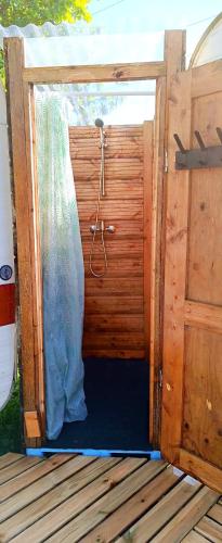 une douche dans une cabine en bois avec un rideau dans l'établissement L'échappée Belle, à Saint-Maudez