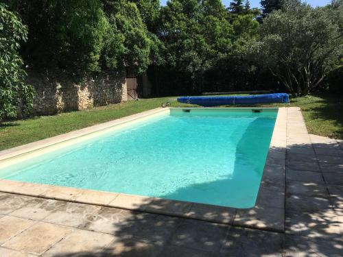 une piscine avec de l'eau bleue dans une cour dans l'établissement le mas rocamour, à Roquemaure