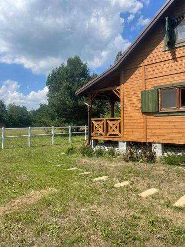 a wooden cabin with a porch and a fence at Domek w Sosnach in Błonie