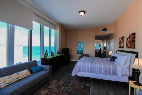 een slaapkamer met een bed, een bank en ramen bij Castle PH15 Spacious Penthouse with Balcony, Beach Access, Pool, Tennis, Free Parking in Miami Beach