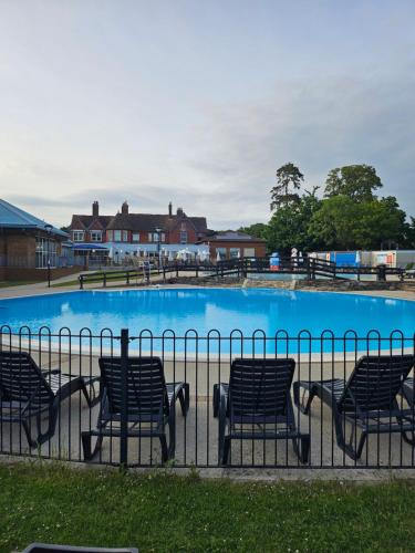 a group of chairs sitting next to a swimming pool at New Forest 2-Bed Premium Holiday Home, Hoburne Bashley Holiday Park,New Milton, Park Leisure Pass at an additonal cost in New Milton