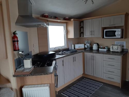 uma pequena cozinha com fogão e micro-ondas em Taid's Retreat Silversands Cove beach lossiemouth em Lossiemouth