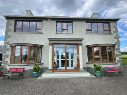 a house with two chairs in front of it at Carrigadaggen Lodge in Ballynagrallagh