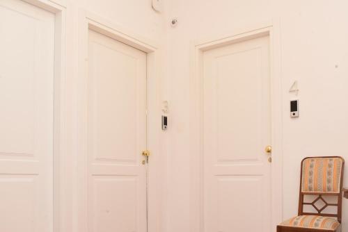 a room with two white doors and a chair at Casa FEREMI in Cavallino di Lecce