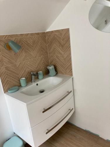 La salle de bains est pourvue d'un lavabo blanc et d'un mur en bois. dans l'établissement Villa très proche de la plage, à Cabourg