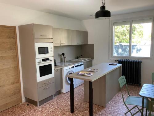 - une cuisine avec des appareils électroménagers blancs et une table dans l'établissement Villa très proche de la plage, à Cabourg