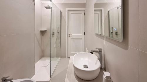 a white bathroom with a sink and a shower at Casa FEREMI in Cavallino di Lecce