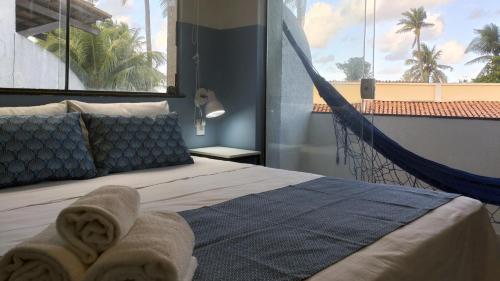 a bedroom with a hammock bed and a large window at FAROL BEACH Suítes in Salvador
