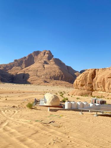 a building in the desert with a mountain in the background at Scarlet Luxury Camp Wadi Rum in Wadi Rum