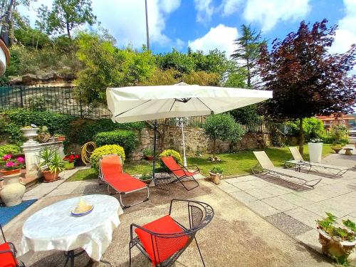 a patio with a table and chairs and an umbrella at La Maison des Rèves -Langhe Piemonte in Torre Bormida