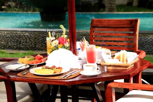a wooden table with plates of food on it at Kubu Garden Suites & Villas Nusa Dua in Nusa Dua