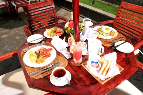 a table with plates of food and drinks on it at Kubu Garden Suites & Villas Nusa Dua in Nusa Dua