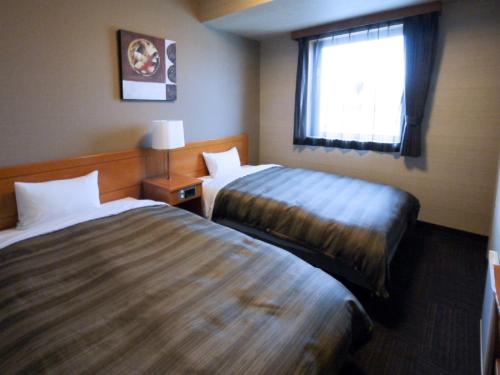 a hotel room with two beds and a window at Hotel Route-Inn Yonezawa Ekihigashi in Yonezawa