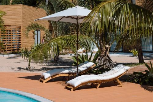 a group of lounge chairs with an umbrella next to a pool at Sentidos Beach Retreat in Miramar