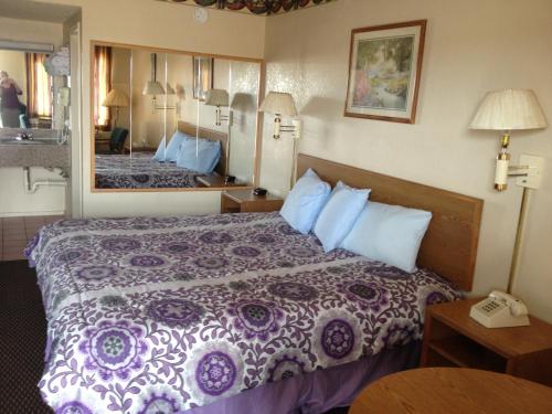 una habitación de hotel con una cama y un espejo en Crown Inn Grand Prairie, en Grand Prairie