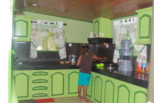a woman preparing food in a green kitchen at Familyhouse in Negombo