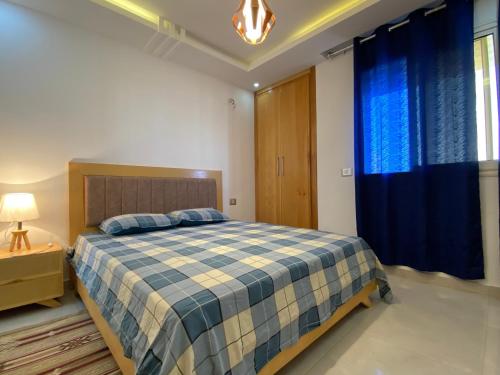 a bedroom with a bed with a blue and white blanket at Appartement ezzouhour DAR SAMMOUD in Kelibia