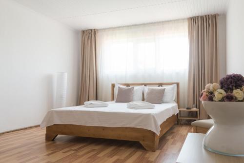 a bedroom with a bed with white sheets and a window at Pensiunea Știuca Șchioapă in Băltenii de Sus