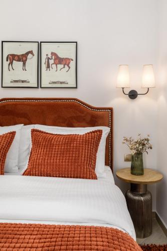 a bedroom with a bed and three pictures of horses on the wall at Meydani Suites in Litochoro
