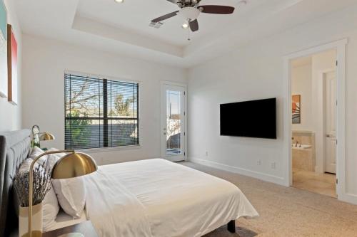 a white bedroom with a bed and a flat screen tv at Bright Home in East ATX - 3BR - Cowboy Pool in Austin