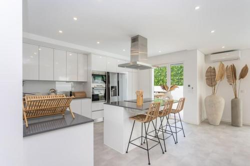 a kitchen with white cabinets and a island with chairs at Casa John Lisboa-Piscine chauffée en option in Charneca