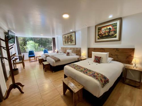 a hotel room with two beds and a chair at Hotel Tara Machupicchu in Machu Picchu