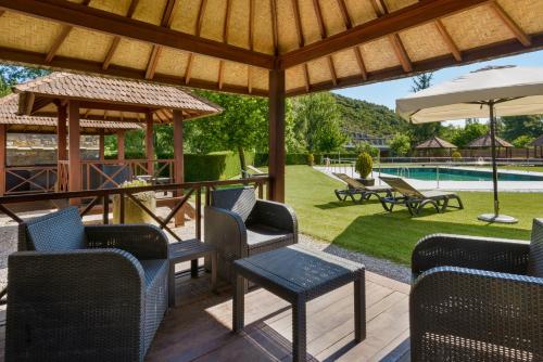 a patio with chairs and an umbrella and a pool at Hotel & Spa Monasterio de Boltaña in Boltaña