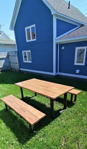 a picnic table and bench in front of a blue house at Lands End Vacation Home in Twillingate