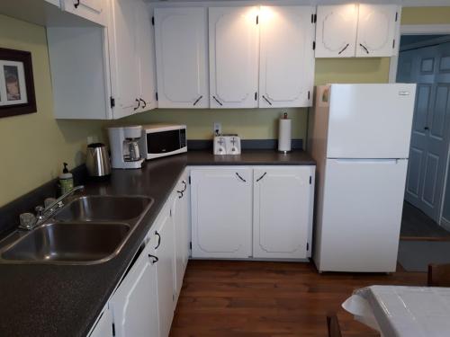 a kitchen with white cabinets and a sink and a refrigerator at Lands End Vacation Home in Twillingate