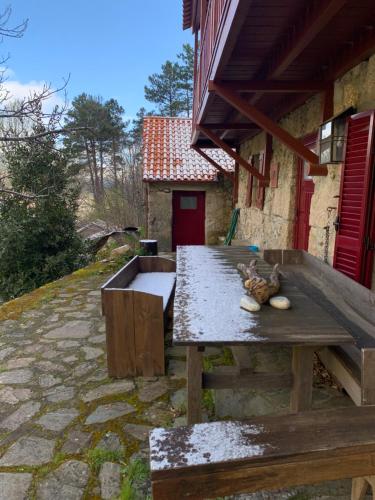 a wooden picnic table in front of a building at Chalé na Montanha Casa de Baixo in Manteigas