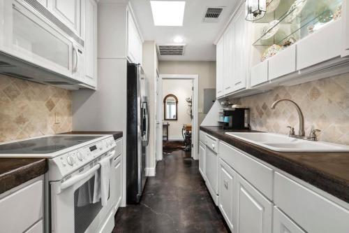 a kitchen with white cabinets and a sink at Historic 2 bd Home Patio DT Fredericksburg in Fredericksburg