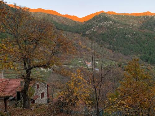 a house on a hill with mountains in the background at Chalé na Montanha Casa de Baixo in Manteigas