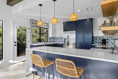 a kitchen with blue cabinets and stools at Atlantis - Front Row View of Lake Travis in Leander