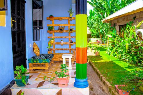 a house with a colorful column with a bench and plants at Arusha Jua Eco Home- on coffee farm in Arusha